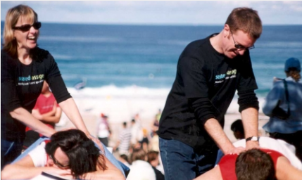 Two people receive a table massage at the beach from Seated Massage at an event