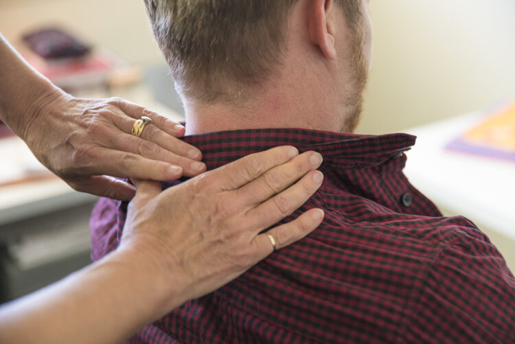 A close up of hands massaging a man's shoulders and neck