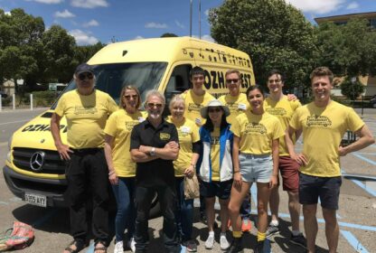 A group of volunteers wearing yellow tshirts standing with an OzHarvest van