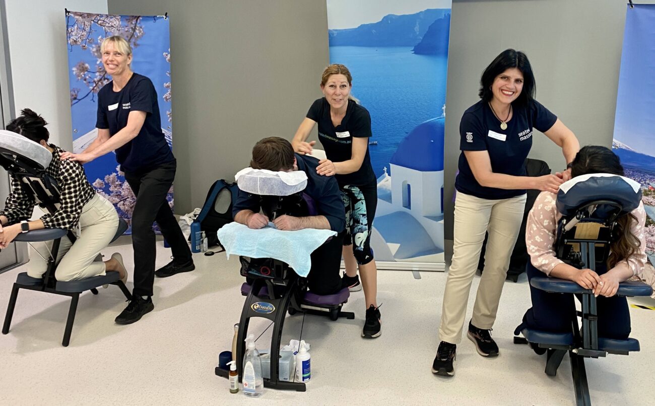 three Massage Practitioners giving chair massages at an event