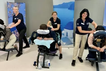 three Massage Practitioners giving chair massages at an event