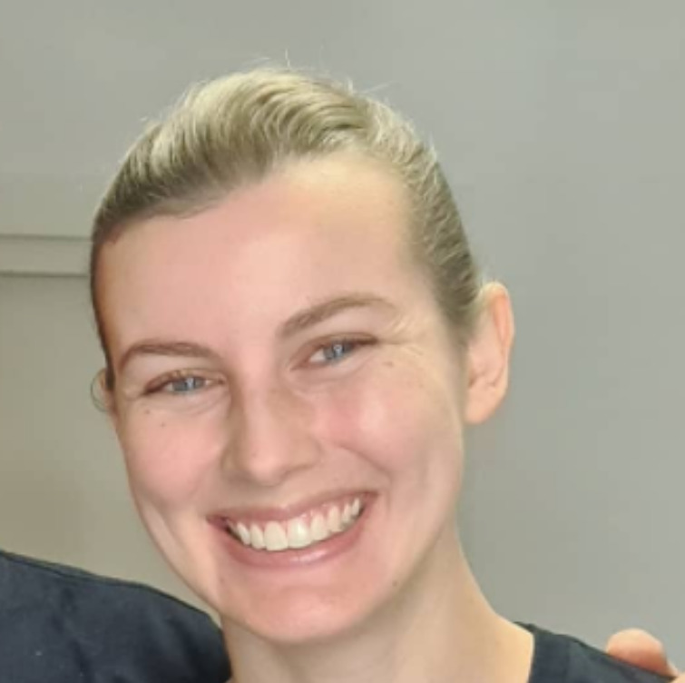 A young woman with blonde hair smiles at the camera