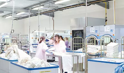 Staff in a large laundry room washing and folding laundry